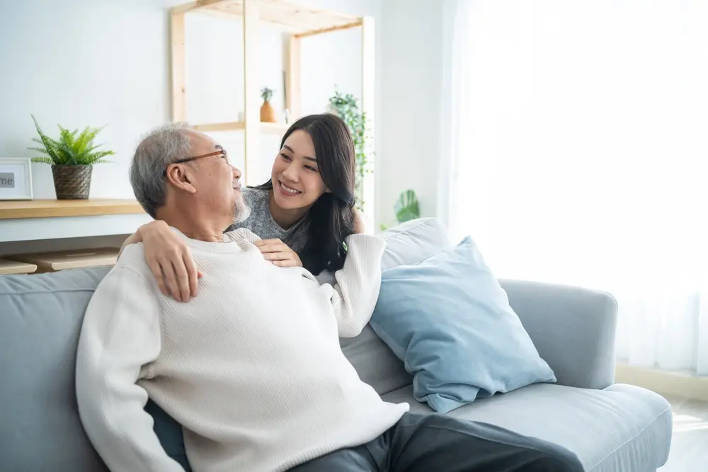 Asian family with young daughter greeting and hugging older father.