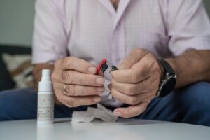 Grandfather Cleaning His Hearing Aids So He Can Listen.